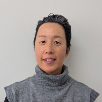 Person in grey turtleneck top against plain light background